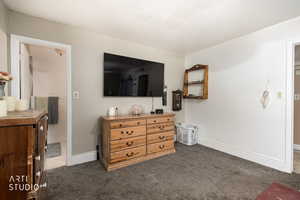 Bedroom with dark carpet and baseboards