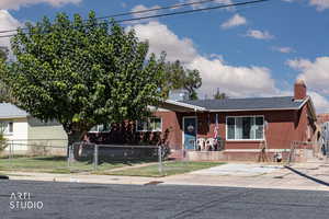 View of front facade with a chimney, a fenced front yard, a gate, and brick siding