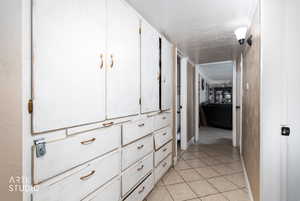 Hallway with light tile patterned floors and a textured ceiling