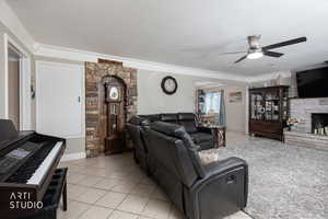 Living area featuring light tile patterned floors, a fireplace, a textured ceiling, and ceiling fan