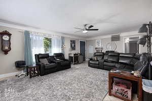 Living room featuring crown molding, ceiling fan, and light tile patterned floors