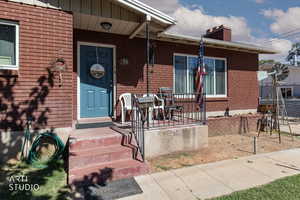 Entrance to property featuring a chimney and brick siding