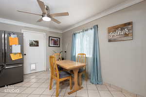 Dining area with crown molding, light tile patterned floors, and a ceiling fan