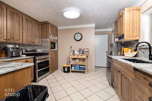 Kitchen featuring decorative backsplash, brown cabinets, stainless steel appliances, light tile patterned floors, and a textured ceiling