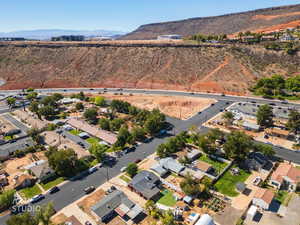 Aerial view of property and surrounding area featuring nearby suburban area and a mountainous background