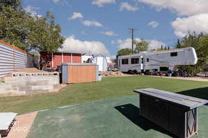 View of grassy yard featuring a storage shed and a patio area