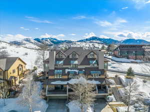 Snow covered rear of property with a chimney, a mountain view, and stairs