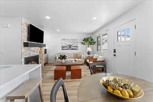 Living room with a stone fireplace, light wood-style floors, and recessed lighting