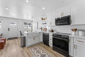 Kitchen with electric range, white cabinetry, open shelves, a peninsula, and stainless steel microwave