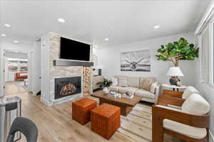 Living room featuring a stone fireplace, light wood finished floors, and recessed lighting