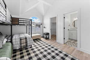 Bedroom featuring a walk in closet, light wood-style floors, high vaulted ceiling, and ensuite bathroom