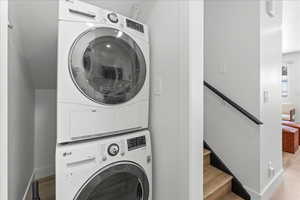 Washroom with light wood-style flooring and stacked washer / dryer