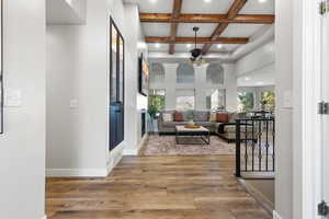 Hall featuring coffered ceiling, beamed ceiling, light wood-style flooring, recessed lighting, and a high ceiling