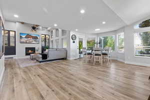 Living area with recessed lighting, a glass covered fireplace, and light wood-style flooring