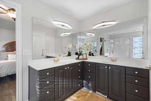 Primary bathroom with double vanity, healthy amount of natural light, and a shower stall