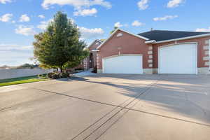 View of front facade featuring brick siding, concrete driveway, and a 3-car garage