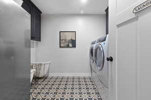 Laundry area with cabinet space, independent washer and dryer, and tile patterned floors