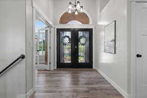 Entrance foyer featuring french doors, wood finished floors, and a towering ceiling