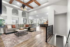 Living area with recessed lighting, beam ceiling, hardwood / wood-style floors, a towering ceiling, and coffered ceiling