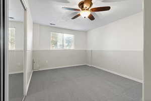 Carpeted empty room featuring a ceiling fan and baseboards