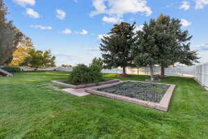 View of fenced backyard with vegetable garden.