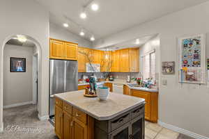 Kitchen featuring rail lighting, white appliances, lofted ceiling, light countertops, and decorative backsplash