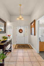 Entryway featuring light tile patterned flooring and a chandelier