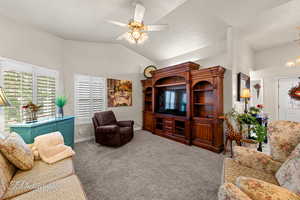 Living area with carpet floors, lofted ceiling, and ceiling fan