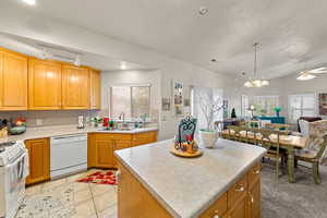 Kitchen with white appliances, light countertops, decorative backsplash, light tile patterned floors, and a chandelier