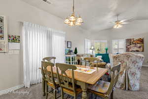 Carpeted dining space featuring vaulted ceiling, a chandelier, and ceiling fan