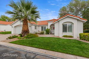 Mediterranean / spanish home with a front lawn, stucco siding, driveway, and a garage