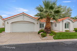 Mediterranean / spanish-style house featuring a tiled roof, stucco siding, driveway, and an attached garage