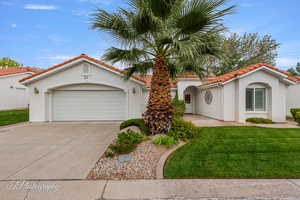 Mediterranean / spanish home with a front yard, concrete driveway, stucco siding, a tile roof, and a garage