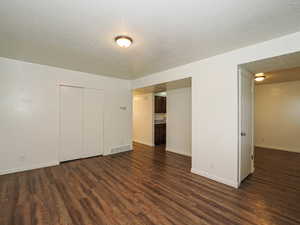 Unfurnished room featuring a textured ceiling and dark wood-style floors