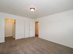 Unfurnished bedroom featuring dark carpet, a textured ceiling, and a closet