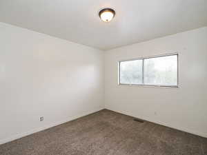 Spare room with dark colored carpet and baseboards