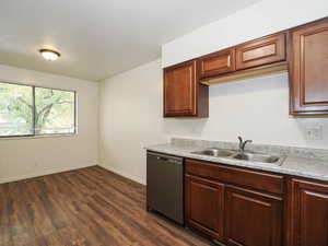 Kitchen featuring stainless steel dishwasher, wood-style floors, light countertops, and a textured ceiling