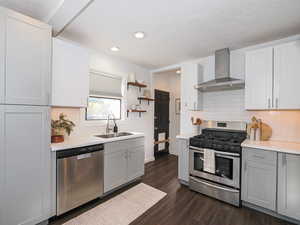 Kitchen featuring subway tile backsplash, stainless steel appliances, light gray cabinetry, open shelves, and recessed lighting, view to side door and access to basement stairwell