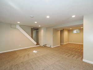 Finished below grade area with light carpet, recessed lighting, and stairway