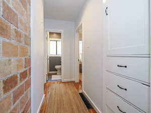 Hall with light wood flooring and built-in storage shelves and drawers