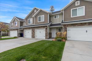 Craftsman inspired home featuring stone siding, driveway, board and batten siding, a front lawn, and an attached garage