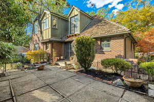 Rear view of house featuring brick siding, a patio, a gate, and stucco siding