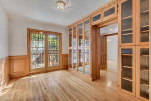 Doorway to outside featuring wainscoting and wood finished floors