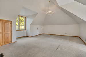 Bonus room with light colored carpet and lofted ceiling