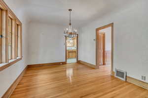 Unfurnished dining area with a chandelier, light wood-type flooring, and healthy amount of natural light