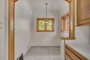 Kitchen with tile counters, hanging light fixtures, and decorative backsplash