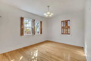 Empty room featuring healthy amount of natural light, wood finished floors, and a chandelier