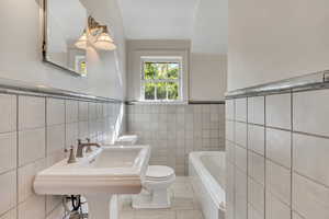 Full bathroom featuring tile patterned flooring, a wainscoted wall, tile walls, and a garden tub