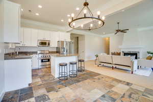 Kitchen with crown molding, appliances with stainless steel finishes, open floor plan, a center island, and a breakfast bar