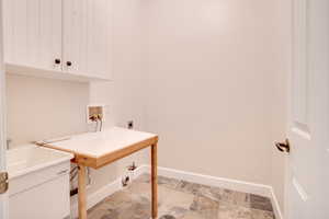Laundry area featuring hookup for an electric dryer, hookup for a washing machine, and light stone finish flooring